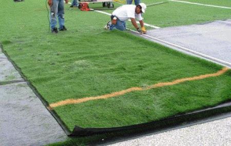 Workers install a piece of Field Turf at Kingston Stadium on Wednesday afternoon. (Photo by Jeff Linder)